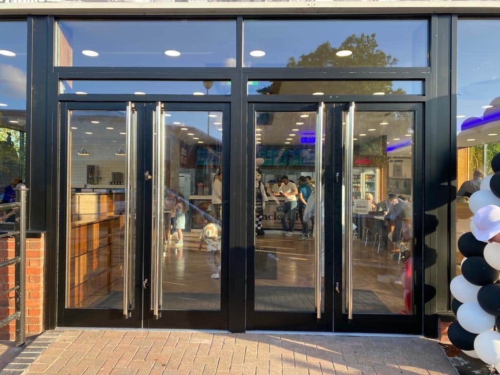 Double glazed entrance doors with full-height pull handles beneath a glazed fanlight, ready for an opening day.