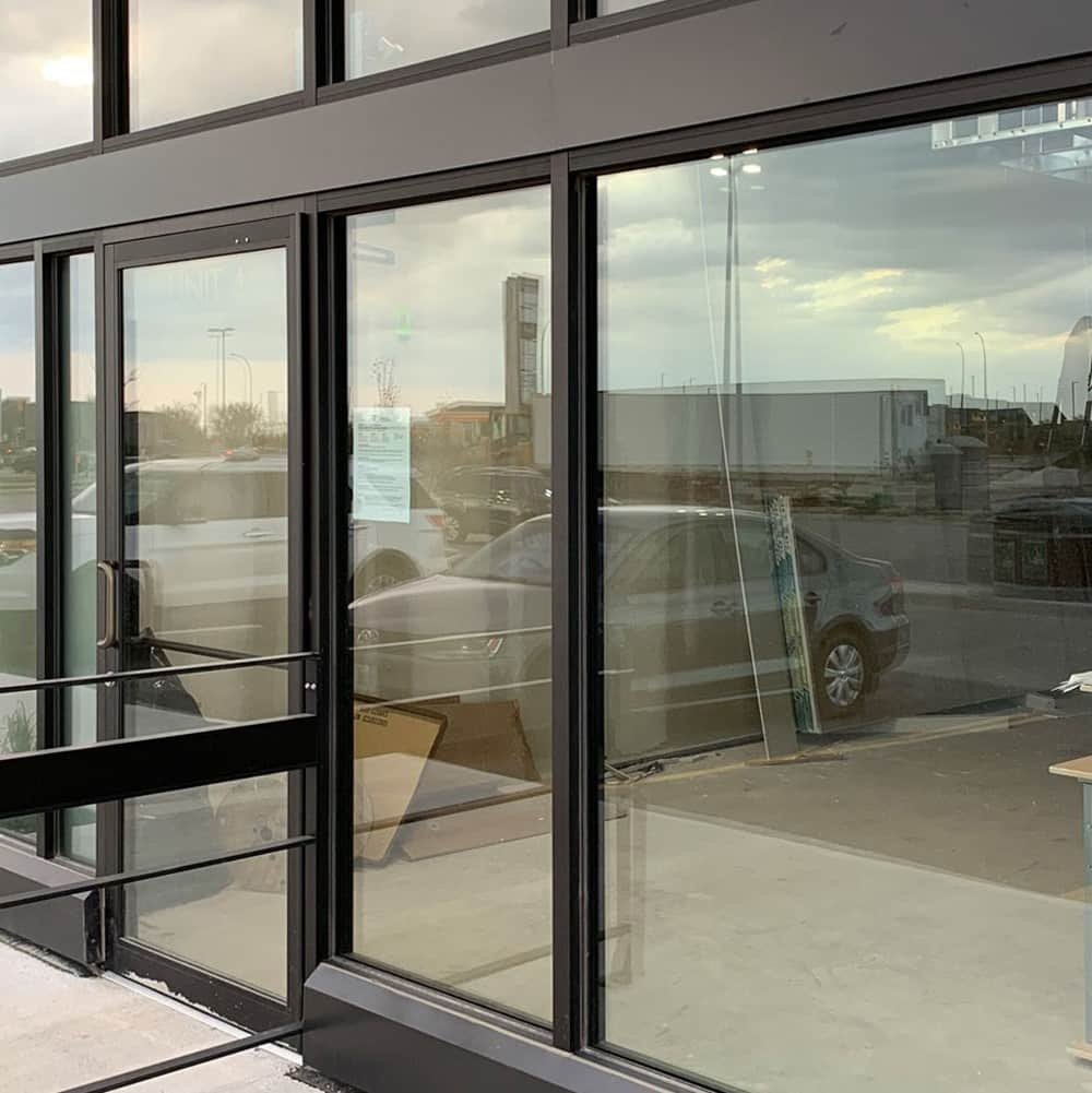 Dark aluminium framing and a glazed door going into a commercial unit, with glass panels still stacked inside.
