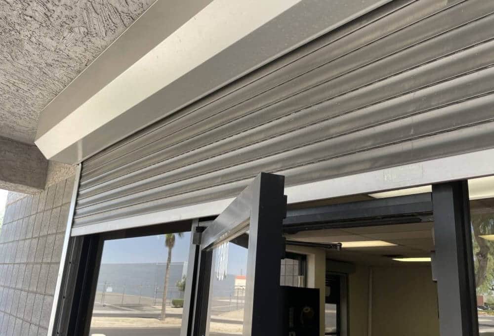 Roller shutter and box fitted above a dark aluminium glazed entrance, the door standing open beneath it.